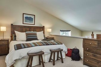 Cozy loft bedroom in Four Seasons 1 8 with a wooden king bed, matching nightstands, and a dresser.