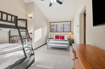 A cozy children's bedroom in Highlands Slopeside 502 with bunk beds, a single bed, and a scenic window view of snow-covered slopes.