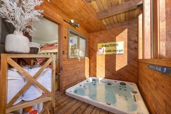 A private hot tub is located on a wooden deck next to a room with bunk beds.