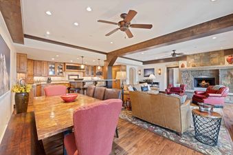 An expansive open-concept living area at The Charter E340, showcasing the connected kitchen, dining room, and lounge with a stone fireplace and rustic wooden accents.