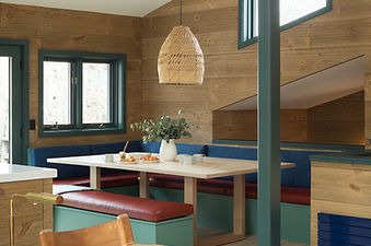 A rustic yet modern dining and seating area at Sundown Clear Creek with wood-paneled walls, built-in bench seating, and a leather armchair.