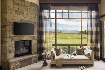 Cozy daybed by a large window with mountain views and a stone fireplace.