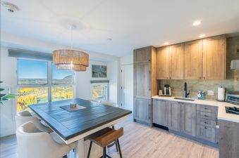 The Peaks Penthouse 434 boasts a stunning mountain view from the dining area, featuring a modern, rustic kitchen with a breakfast bar.