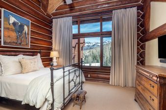 The bedroom at Townhomes on the Creek 139 features rustic log walls and a beautiful mountain view.