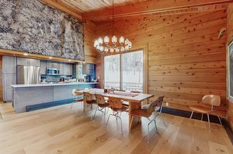 A spacious, rustic-modern dining area and kitchen at Wood Road House with wooden walls and floors.
