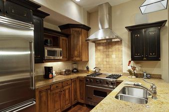 The fully equipped kitchen at Silver Star 1303 features stainless steel appliances, granite countertops, and a blend of rustic and dark-stained cabinetry.