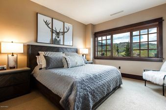 A serene bedroom at Arrowleaf Lodge 109 with a large bed, stylish decor, and a scenic mountain view through a wide window.
