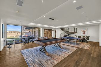 A modern, spacious entertainment room at The Foundry with a pool table, ping-pong table, dining area, and large windows looking out to a scenic landscape.