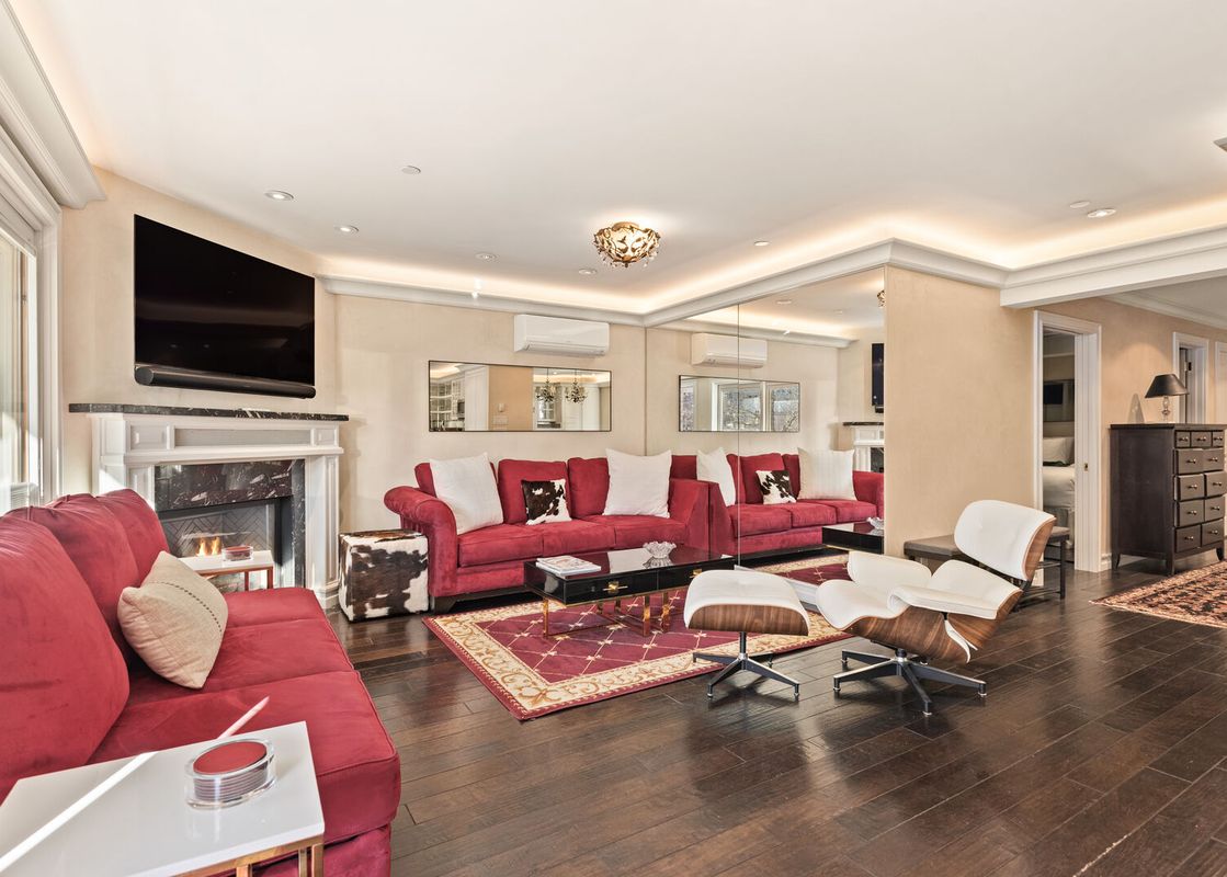 A luxurious and spacious living area in North of Nell Unit 2D featuring red sofas, a fireplace, a flat-screen TV, and contemporary decor.