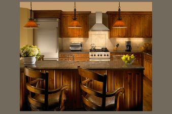 A modern kitchen with wooden cabinetry, granite countertops, and stainless steel appliances.