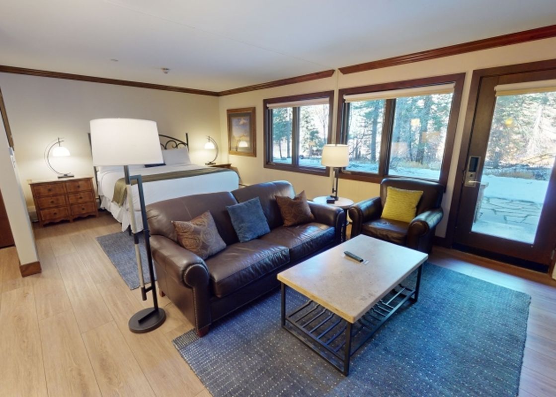 A living room with a couch and a coffee table, with a window looking out to a snow covered outdoor area.