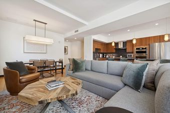 The living room of The Lion W302 features a sectional sofa, a coffee table with magazines, and a large picture window overlooking the mountains.