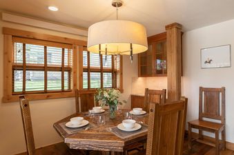 A wooden hexagonal dining table and chairs in Nez Perce A2, illuminated by a drum pendant light.