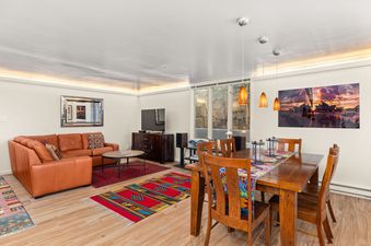 Living and dining space in Chateau Dumont Unit 23 with a cognac leather sofa and a wooden dining table.
