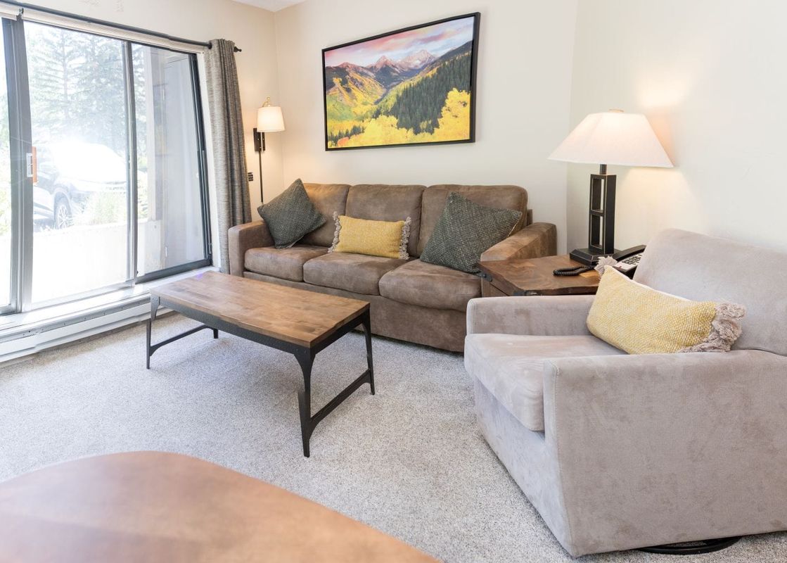 A spacious living area of the Beaver Run Resort Studio with comfortable seating, a coffee table, and large sliding glass doors that lead to the exterior.