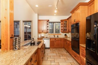 The kitchen at Sawmill Run Lodge features warm wooden cabinetry, granite countertops, modern appliances, and a central island with a cooktop.