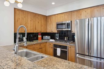 A modern kitchen with stainless steel appliances, a double sink, and wooden cabinets.