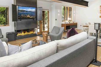 The living room of 1175 A Casolar Del Norte features a gas fireplace and a large sectional sofa with white cushions.