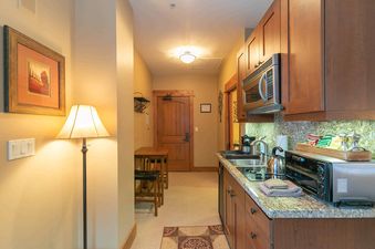 A small kitchenette with a microwave, oven, and a sink.