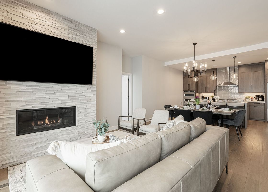 An expansive open concept living space at Hideout Epic View, featuring a living room with a fireplace and television, a dining area, and a modern kitchen.