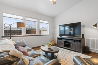 A cozy living room at Destiny Cove with a leather sofa, coffee table, and flat-screen TV, bathed in natural light from large windows.