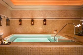 An inviting indoor hot tub area, featuring warm lighting, tiled walls, and decorative elements.