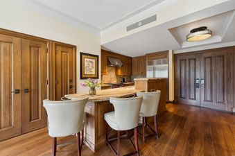 A sophisticated kitchen with wooden cabinetry, granite countertops, and modern appliances, complemented by a kitchen island with seating.