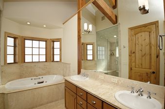 A luxurious master bathroom with a Jacuzzi tub, dual vanity, and a glass-enclosed shower.