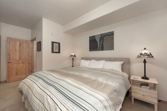 A cozy bedroom featuring a large bed with striped bedding, two nightstands, and decorative lamps.
