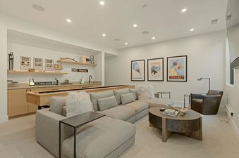 Comfortable lounge area in Sunrise Ridge at Canyons featuring a large gray sectional sofa, a coffee table, a shuffleboard table, and vintage ski posters on the wall.