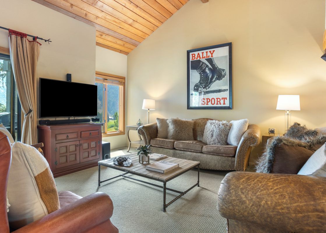 A cozy living room with a TV, comfortable couches, and a coffee table.