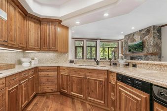 A well-equipped kitchen with wood cabinets, a granite countertop, and a stainless-steel sink