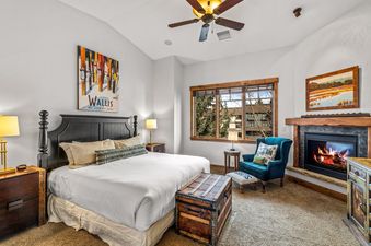 Cozy master bedroom with a king bed, fireplace, and armchair at Cimarron 4.