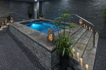 A serene indoor hot tub area at Grand Colorado on Peak 8 Suite Residence, featuring dim lighting, candles, and lush green plants.