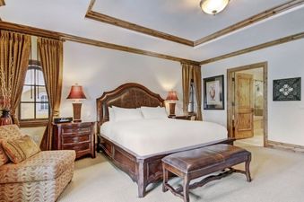 A spacious bedroom in The Arrabelle One Bedroom featuring a large bed with a dark wood frame and headboard, nightstands, and elegant decor.