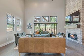 Bright and airy living room at Mayflower Lakeside 9975 featuring a modern stone fireplace, comfortable seating, and high ceilings.