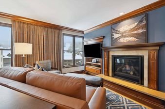 The living area at Park Hyatt 4051 features a comfortable brown leather sofa, a grand fireplace, and a large flat-screen TV.