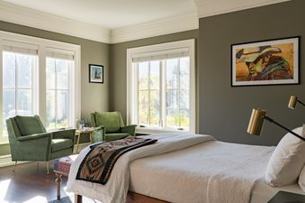An elegant bedroom at Smoky Hollow with green velvet armchairs and a comfortable bed.
