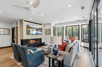 Modern living room at 421 Beaver Creek Lodge with a fireplace, comfortable seating, and forest views through large windows.