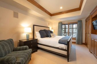 The image features a luxurious bedroom with a comfortable bed, elegant nightstands, and a cozy armchair, all bathed in soft, warm lighting.