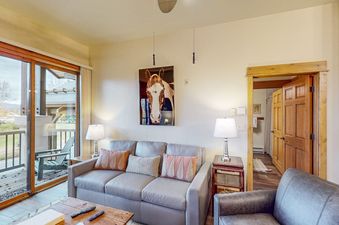 Living area in EagleRidge Lodge 311 with a gray sofa, large sliding glass doors, and a rustic horse portrait on the wall.