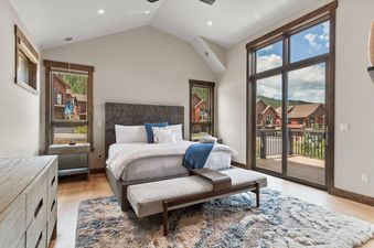 A spacious bedroom in the Independence Lodge featuring a king-sized bed, soft blue and white furnishings, and large windows that offer views of the outdoors.