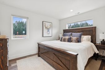 A master bedroom at Quarry B10 featuring a rustic wooden bed frame, white bedding, and a deer artwork on the wall.