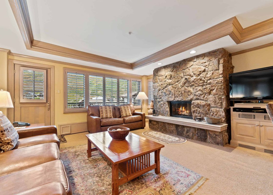 The living room in Lodge Tower 478 2BR features a fireplace, leather couches and a wood coffee table.