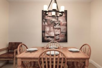 A close-up view of the dining area at Meadow Ridge 18, featuring a light wooden table set with plates and glasses, surrounded by matching wooden chairs.