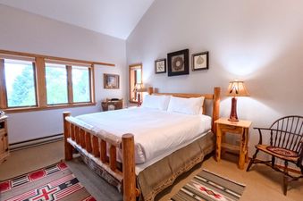 A rustic bedroom with a log bed, warm lamps, and scenic window views in Windriver 12.