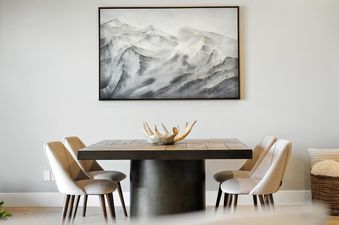 The dining area at Holly Frost Chalet featuring a wooden table with chairs under a large mountain painting.