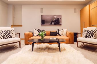 The living room of Silver Queen Chalet features a plush leather couch, a coffee table, and two chairs. The room is decorated with white and black pillows.
