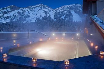 Steaming outdoor pool surrounded by snow-covered mountains at Teton Mountain Lodge and Spa Lodge King during twilight.