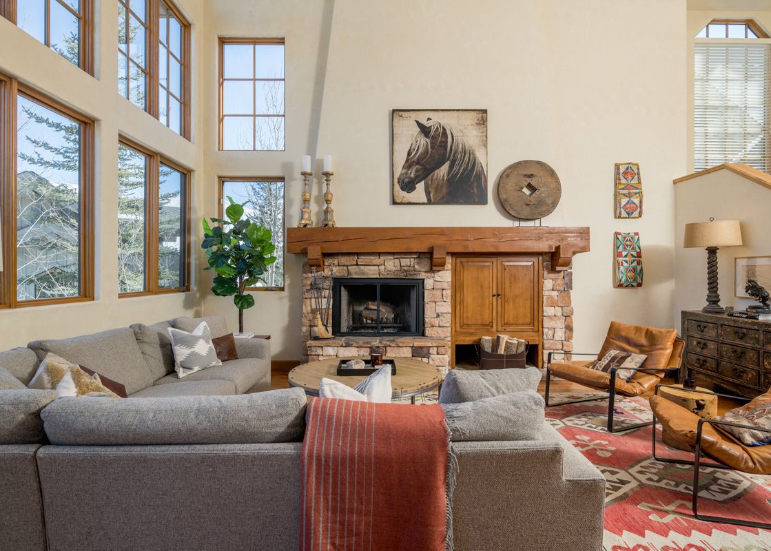 A spacious living room with a fireplace, large windows, and a comfortable sectional sofa.